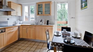 A modern kitchen with wooden cabinets, a gas stove, and a dining area with a polka dot tablecloth. - Duplex 2-bedroom in Brides-les-Bains center, balcony, elevator, pets allowed (Brides-les-Bains)