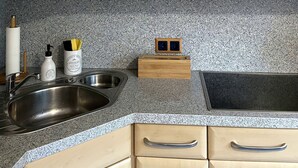 A kitchen with wooden cabinets, a granite countertop, a stainless steel sink, and a double electrical outlet. - Ferienwohnung Ursulastraße (Dinslaken)