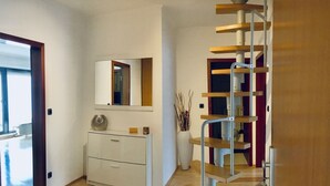 A modern interior with a wooden staircase, a white console desk, and a mirror above it. - Ferienwohnung Ursulastraße (Dinslaken)