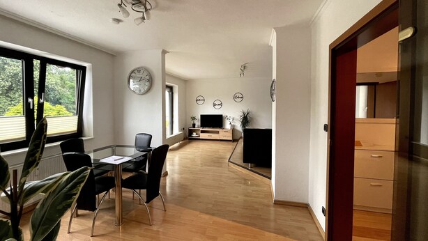 A spacious living area with a dining table, chairs, a TV, and decorative wall art. - Ferienwohnung Ursulastraße (Dinslaken)