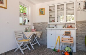 A compact kitchen with white cabinets, a dining table with chairs, and a small countertop. - Amazing apartment in Dugi Rat with house sea view (Dugi Rat)