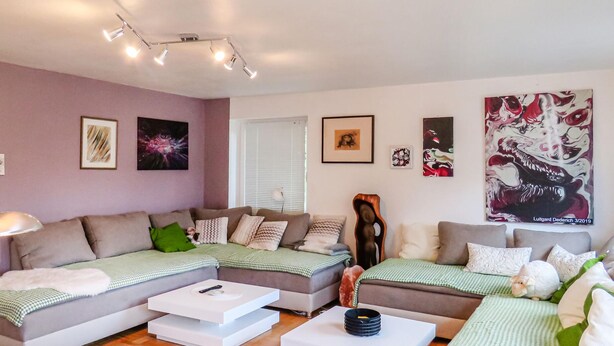 Een moderne woonkamer met een zithoek, een salontafel en kunstwerken aan de wanden.
