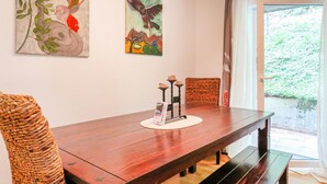Een houten eettafel met banken, een kandelaar en een lijst met een schilderij aan de muur.