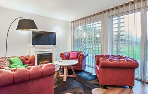 Una sala de estar con chimenea, sofás de cuero, televisor y un ventanal con vistas.
