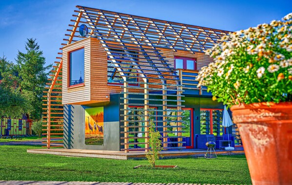 Una casa moderna con fachada de madera, un balcón y un pequeño jardín.