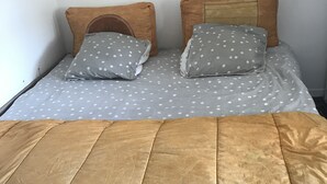 A bed with a brown quilt, two pillows with white polka dots, and a headboard.
