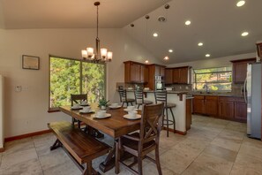 Une cuisine moderne avec des meubles en bois, un îlot central et un coin repas comprenant une banquette et des chaises.