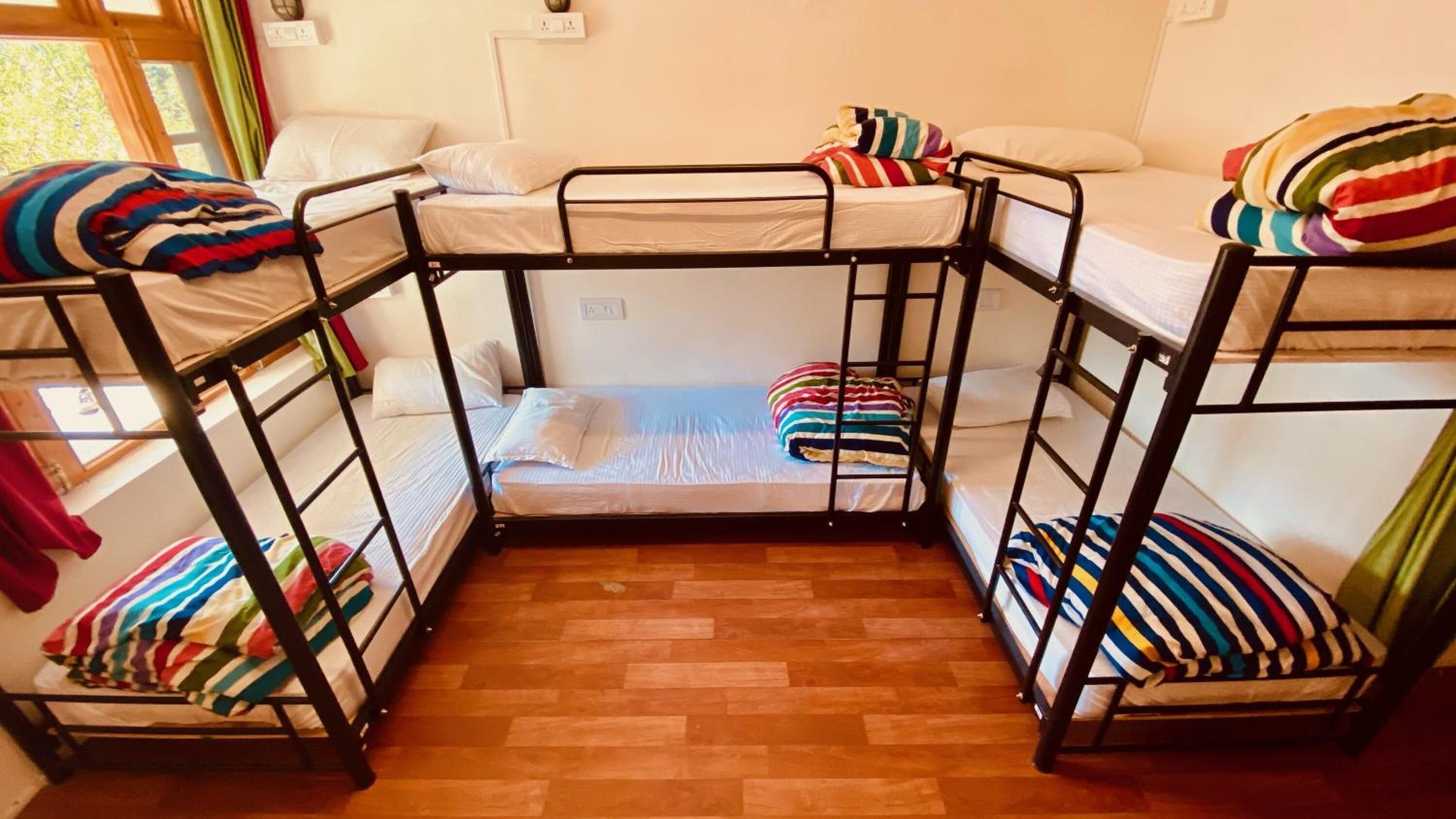 Habitación con literas, suelo de madera y ropa de cama blanca.