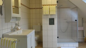 A bathroom with a sink, toilet, shower, and a mirror. - Cozy 2 pers. Vacation apartment "Sunflower" (Irmenach)