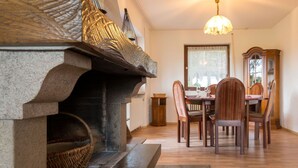 Un coin repas agrémenté d’une cheminée en pierre, d’une table à manger en bois et de chaises.
