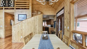 Ein Holzinterieur mit einem langen Esstisch, einer Treppe und einer Küchenzeile.