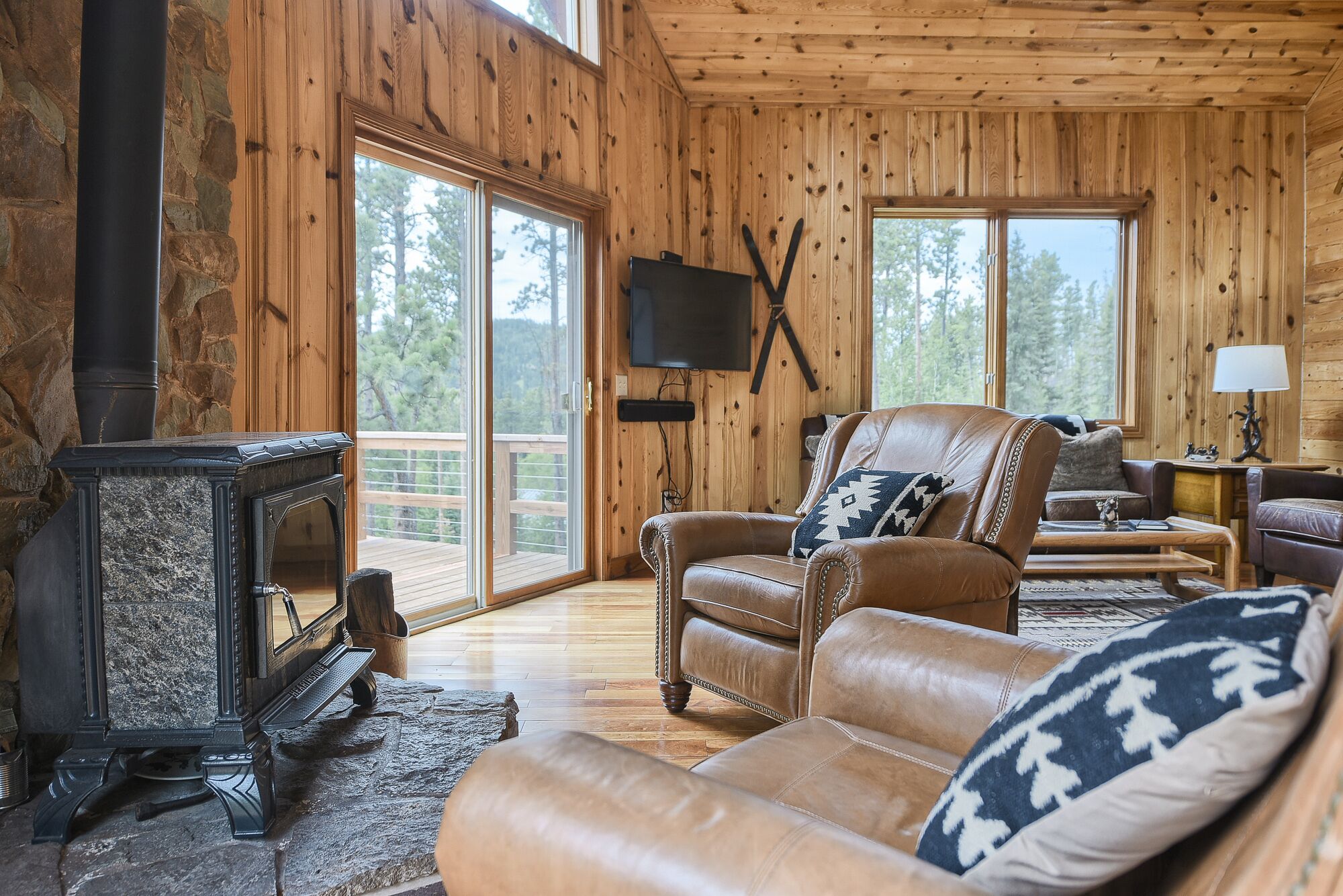 Interior acogedor de una cabaña con chimenea, sofá de cuero y televisor.