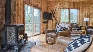 Ein gemütliches Blockhaus-Interieur mit Kamin, Ledersofa und Fernseher.