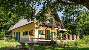 A two-story house with a balcony, surrounded by greenery.