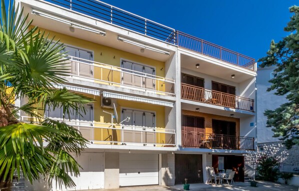 A multi-story residential building with balconies, a garage, and outdoor seating.