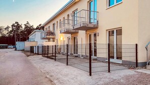 Un edificio residenziale a più piani con balconi, un vialetto recintato e un cielo sereno.