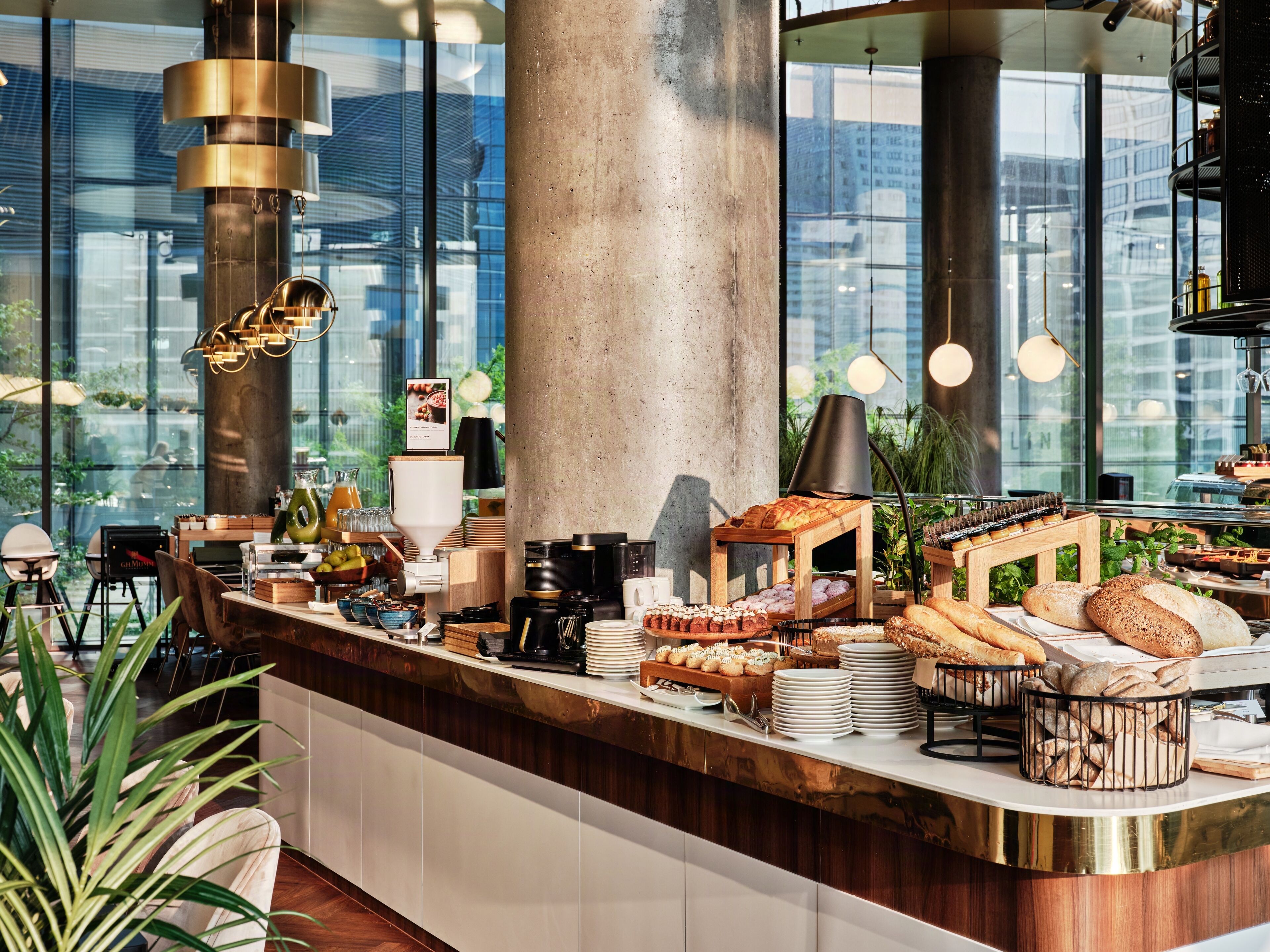 A breakfast buffet with various breads, pastries, and beverages.