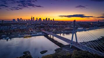 Un horizonte urbano al atardecer, con un puente destacado que cruza un río.