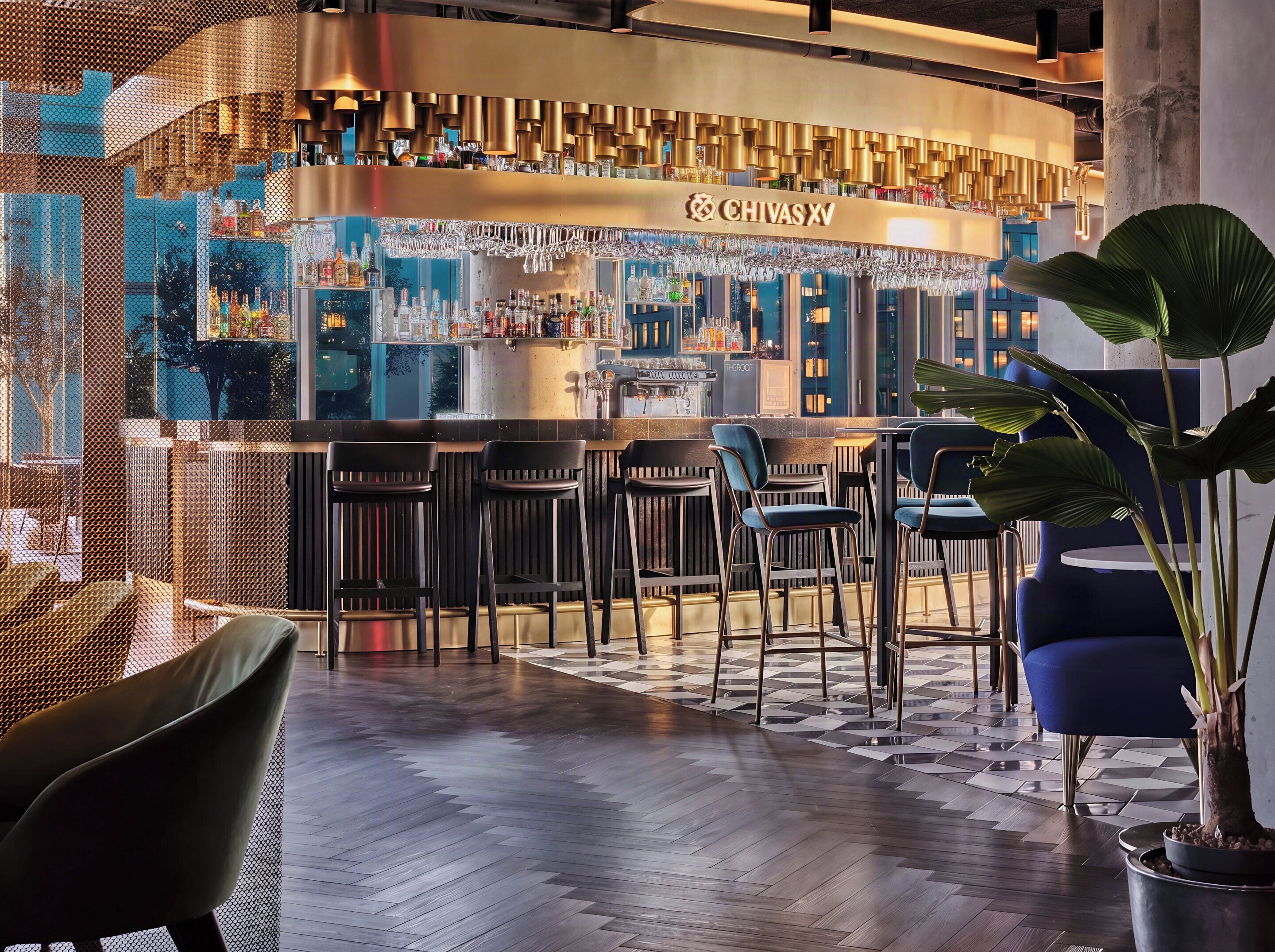 A bar area with a counter, bar stools, and a potted plant.
