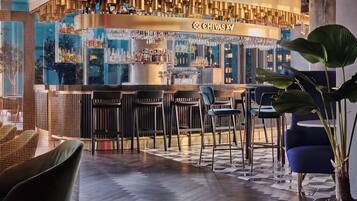A bar area with a counter, bar stools, and a potted plant.