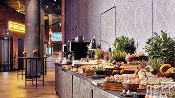 A buffet with various food items, a coffee station, and a bar area with seating.
