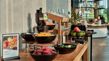 Una mesa de buffet con diferentes alimentos y un dispensador de zumo.