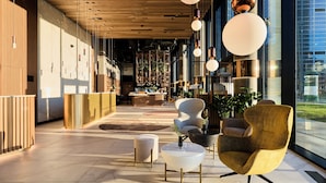 A modern lobby with a reception desk, seating area, and large windows offering views of the city.
