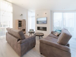 A modern living room with two sofas, a TV, and a small table. - Lovely apartment in villa for 4 guests with WIFI, TV and terrace (Wemeldinge)