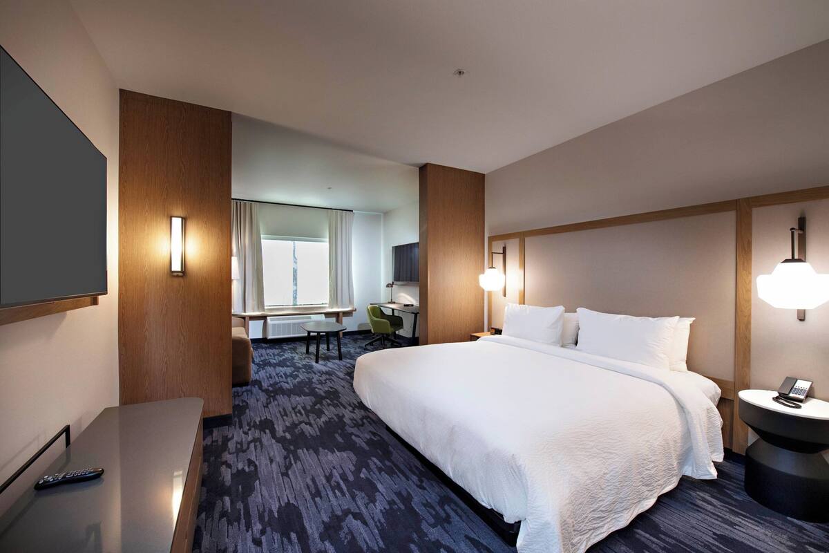 Une chambre d’hôtel avec un grand lit, un bureau, une chaise, une télévision et une fenêtre.
