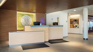 Un área de recepción moderna con techo de madera, mostrador de recepción y una gran pieza decorativa en la pared.