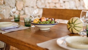 Una mesa de comedor lista con platos, un frutero y vasos.