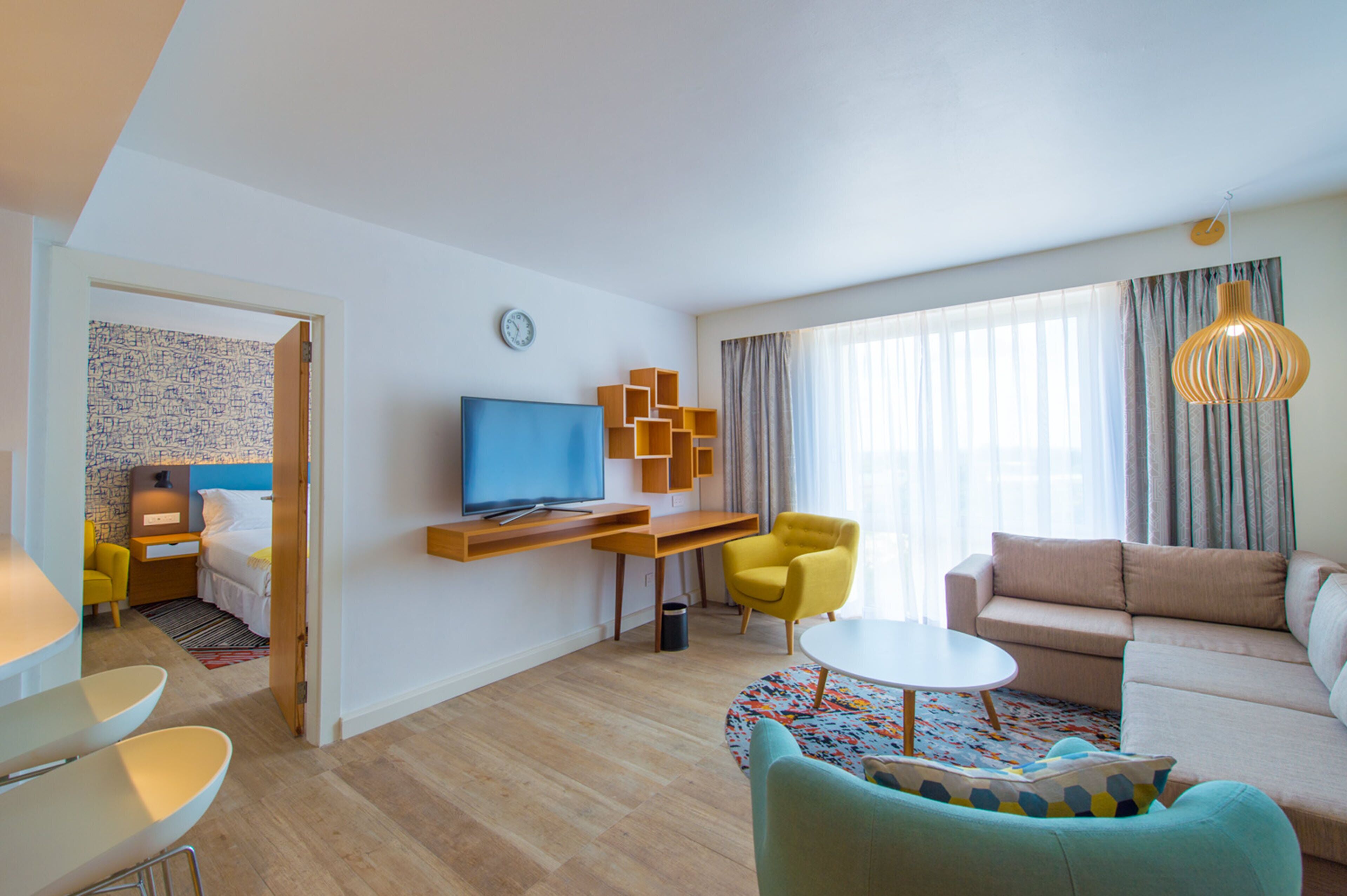 Een moderne woonkamer met een televisie, een bank, een salontafel en een fauteuil.