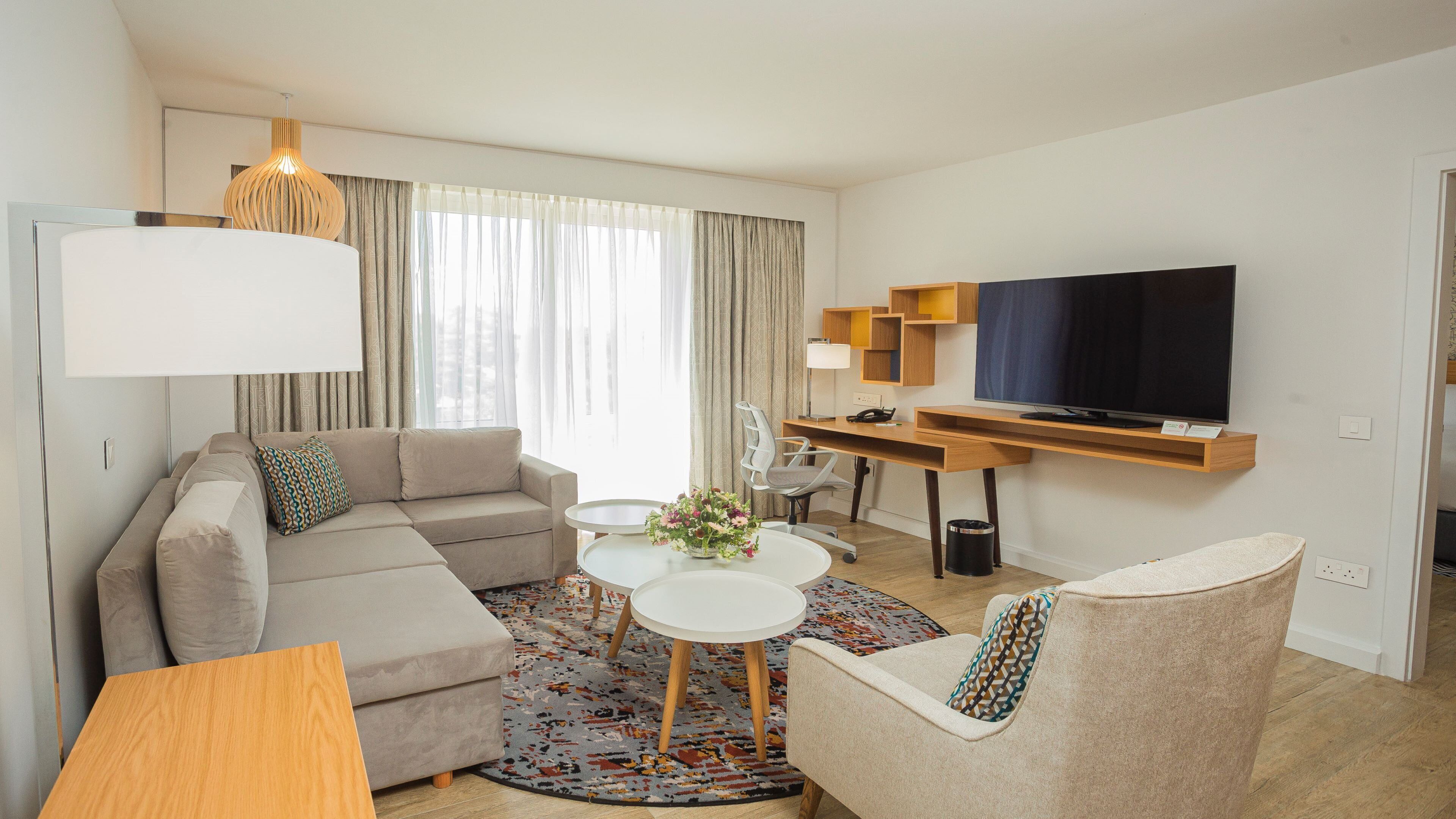A modern living room with a sofa, a coffee table, a TV, and a desk with a computer.