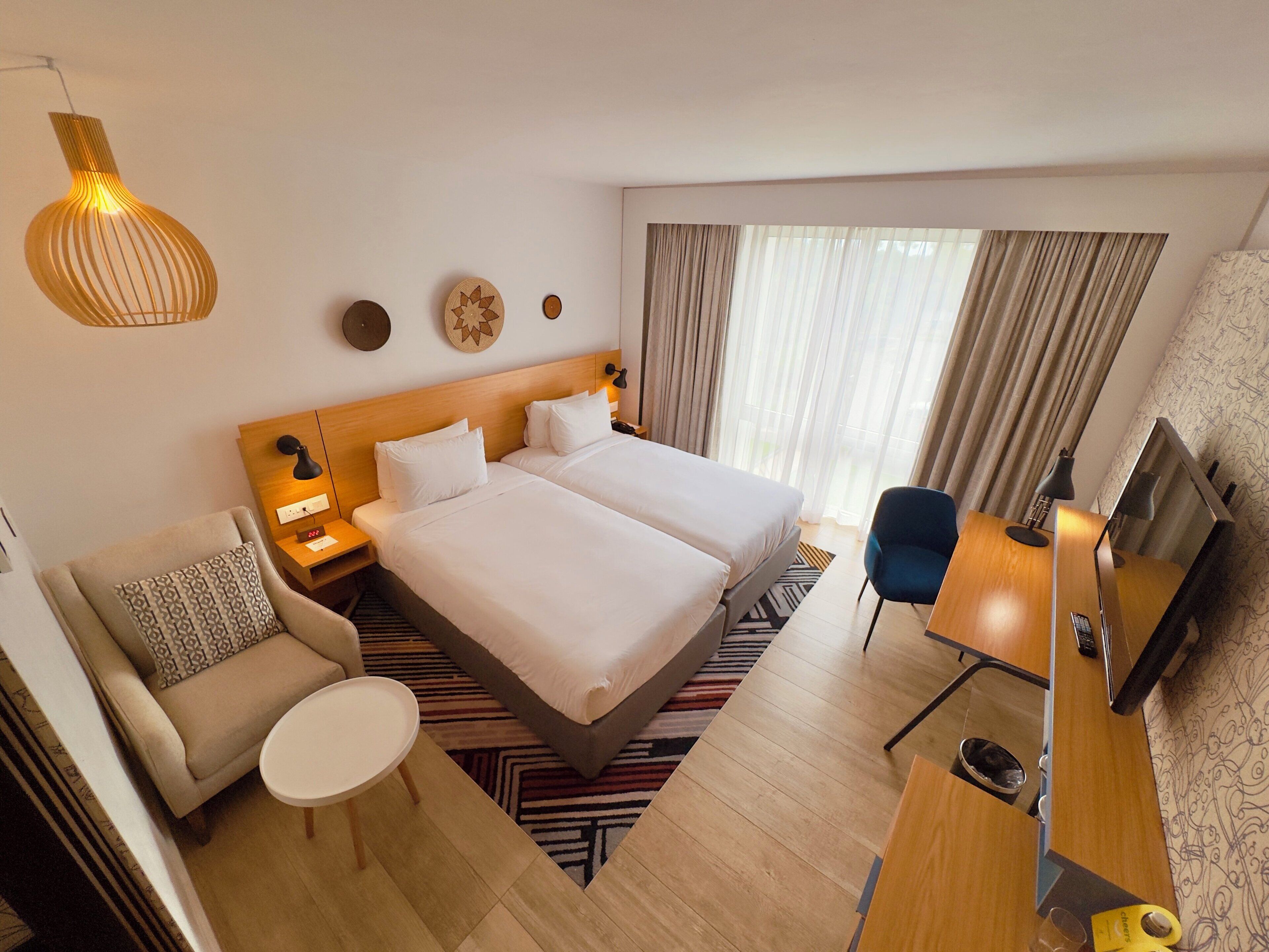 Ein Hotelzimmer mit zwei Betten, einem Schreibtisch, einem Stuhl, einem Fernseher und einer Lampe.