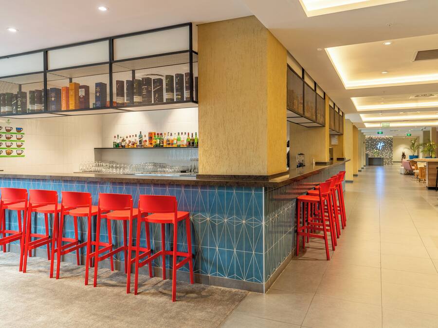 A bar area with red chairs, a counter with various bottles, and a patterned wall.