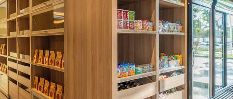 A grocery store interior with wooden shelving stocked with various food items and a refrigerated display case.