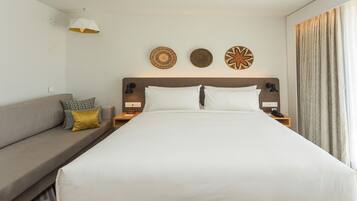 Une chambre d’hôtel avec un lit, une table de chevet, une lampe, une horloge murale et une fenêtre avec des rideaux.