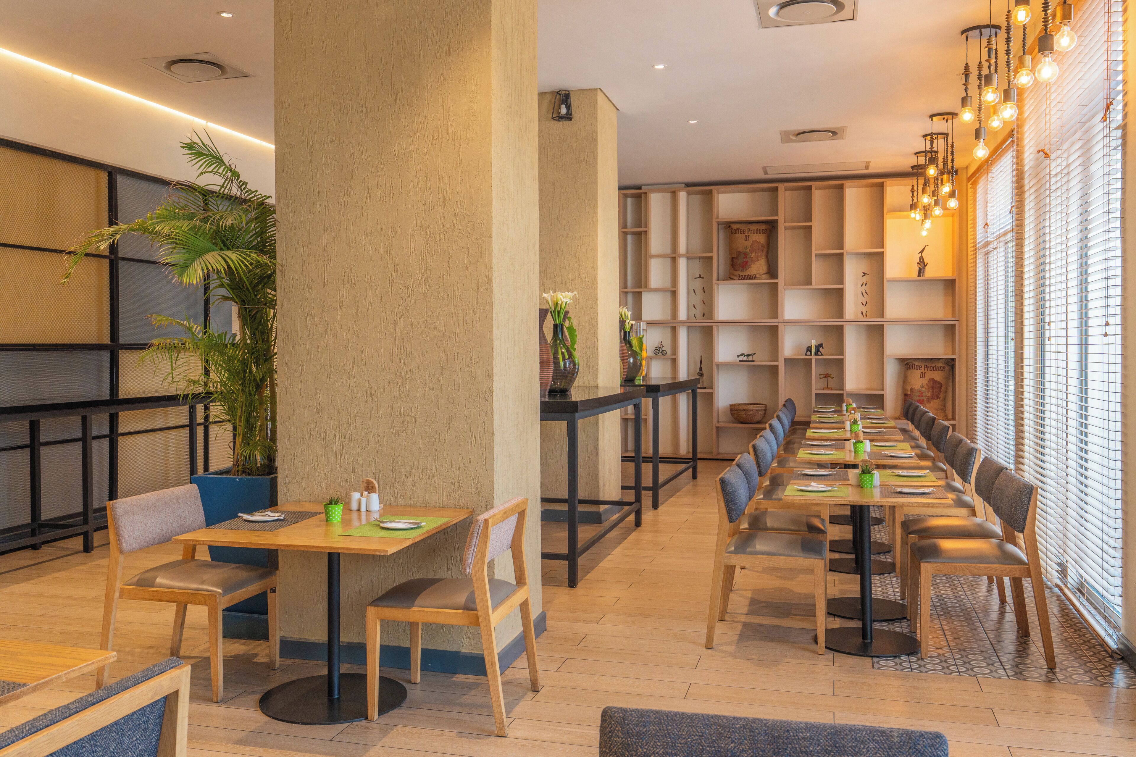 Un restaurant moderne avec des tables et des chaises en bois, des plantes en pot et divers objets décoratifs disposés sur des étagères.
