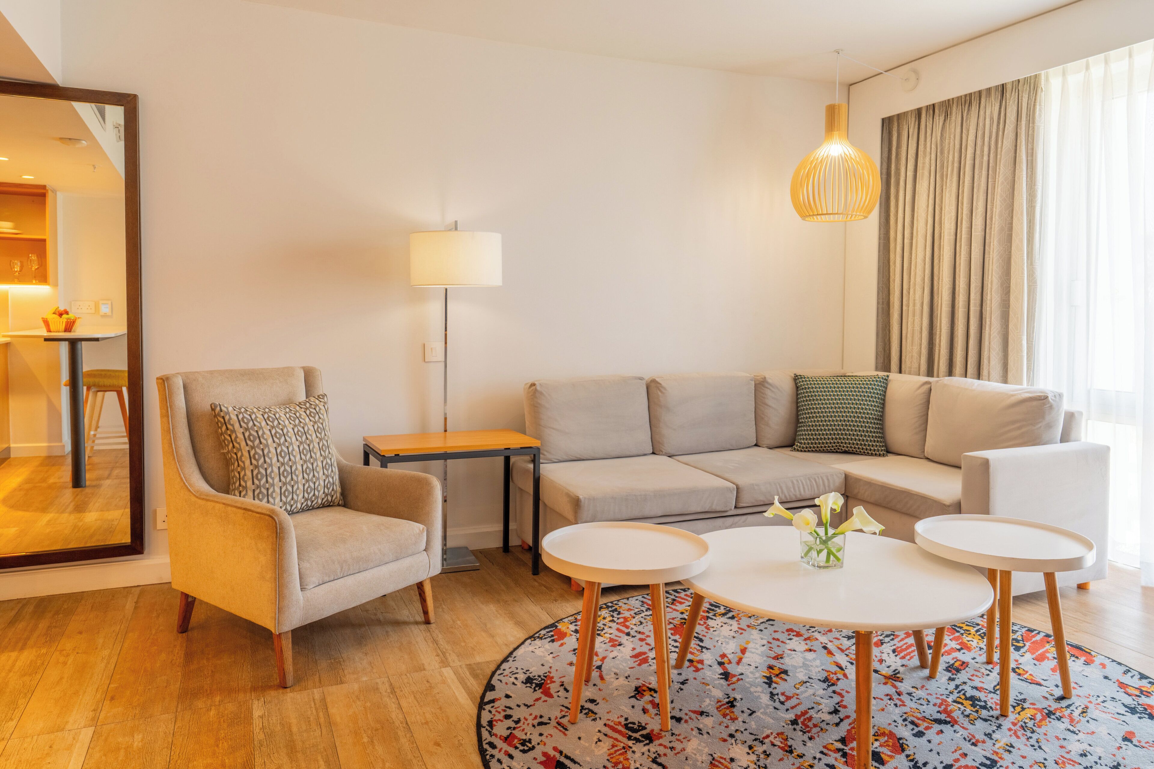 A modern living room with a sofa, armchair, coffee table, and a lamp.
