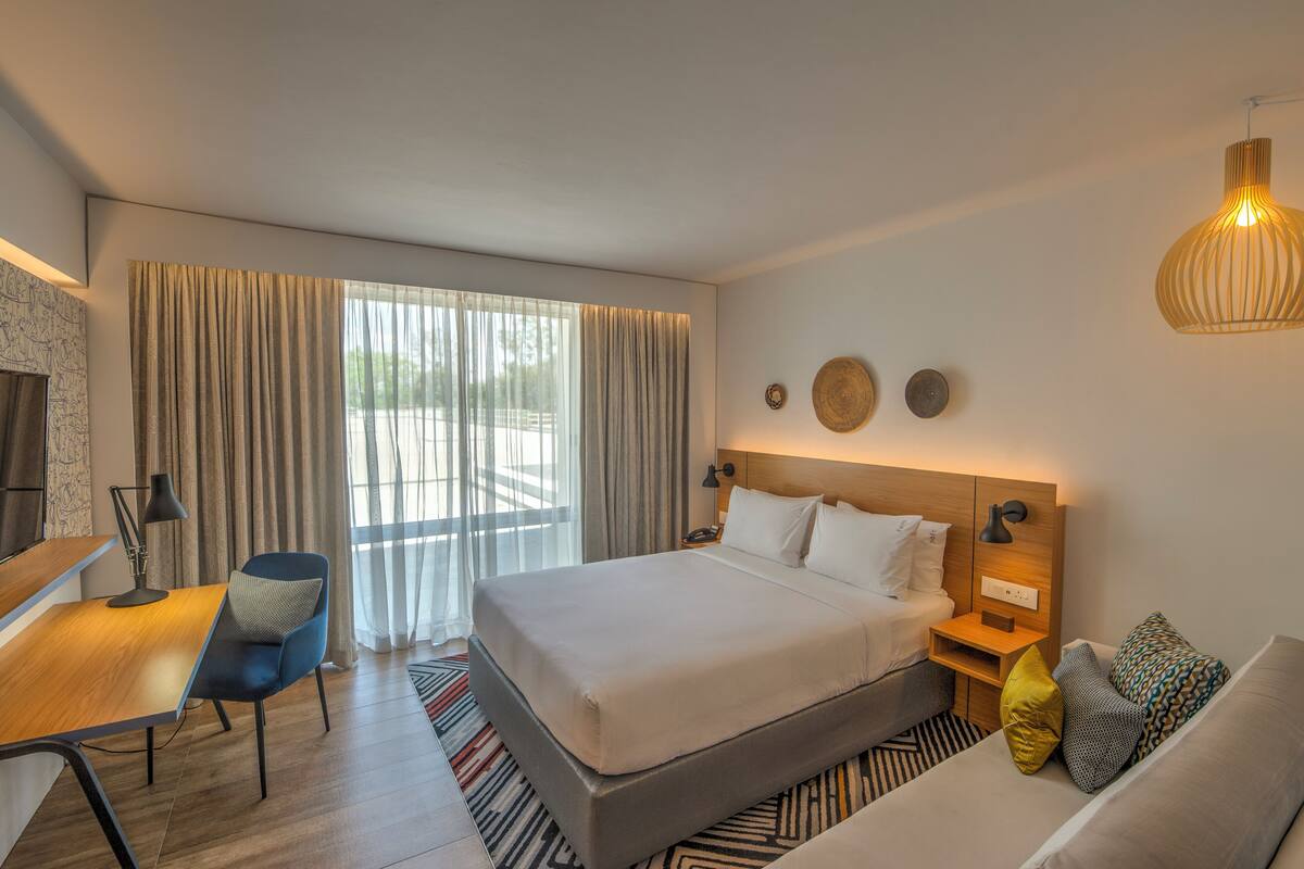 Una camera d'albergo moderna con un letto grande, una scrivania, una sedia e un divano.
