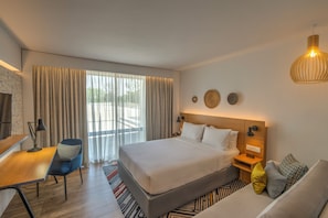 Habitació d'hotel moderna amb un llit gran, un escriptori, una cadira i un sofà.
