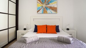 A hotel room with a bed, two bedside tables, a wall-mounted artwork, and a view through a window with a grid pattern.