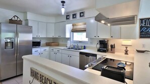 Cocina moderna con armarios blancos, refrigerador de acero inoxidable, lavavajillas integrado y una isla central con tostadora.