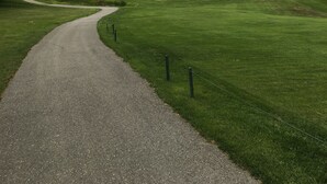 A golf course with a winding path, sand bunkers, and a cloudy sky. - Beautiful Modern A-Frame in Southern Vermont is The Place To BE! (Whitingham)
