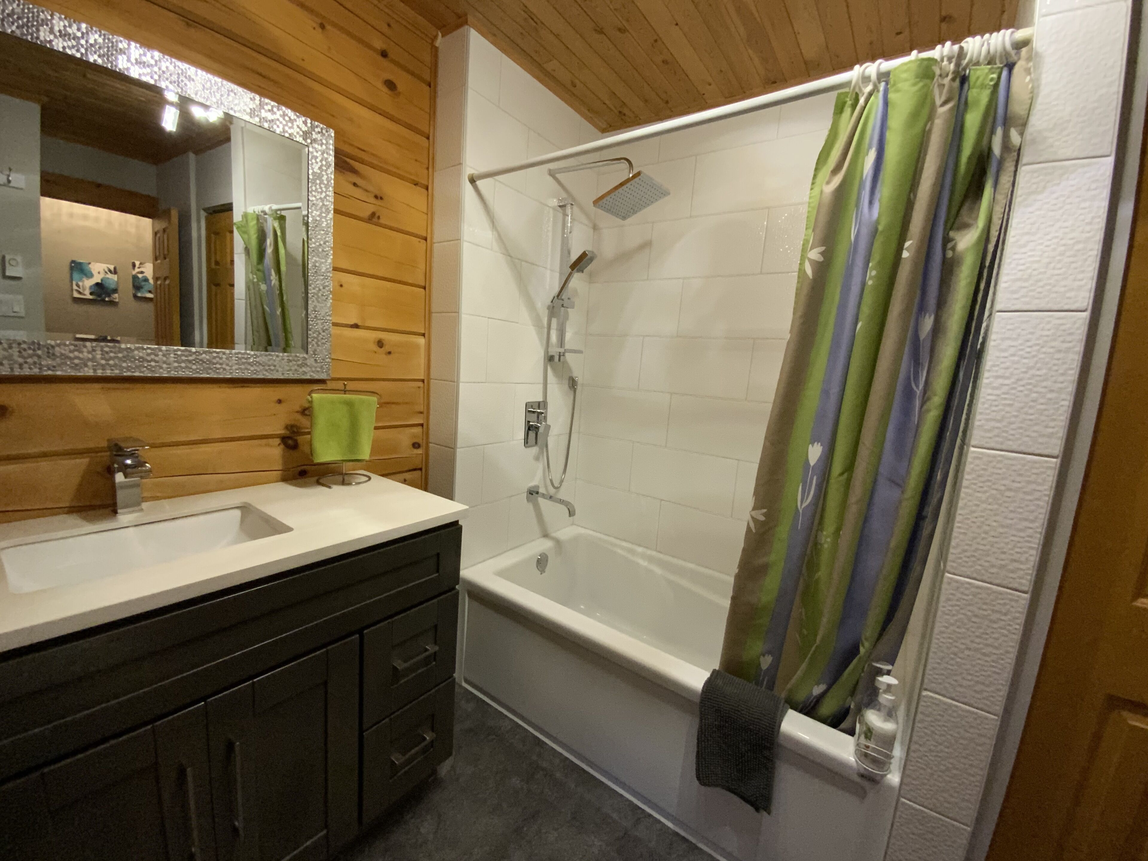 Une salle de bain avec un meuble-lavabo en bois, une baignoire et une douche.