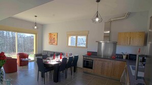 Eine moderne Küche mit Essbereich, großen Fenstern und Blick ins Freie.