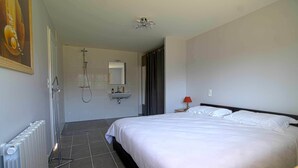 Ein Hotelzimmer mit einem Bett, einem Badezimmer mit Dusche, Waschbecken und Spiegel.