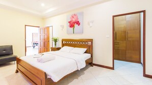 A neatly made bed in a hotel room with a wooden headboard, a ceiling fan, and a large wardrobe. - Majestice Pool Villa 4 Bedrooms (Pattaya)