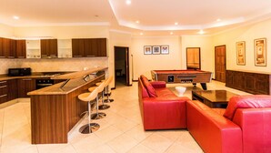 A modern kitchen with a bar area, a pool table, and a red leather sofa. - Majestice Pool Villa 4 Bedrooms (Pattaya)