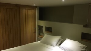 Un dormitorio con una cama grande, armario de madera y estanterías empotradas.
